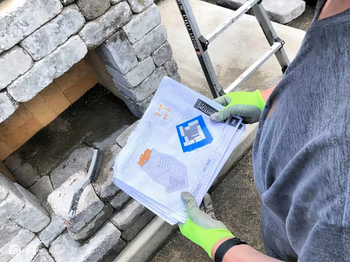 Man holding instructions for building a stone outdoor fireplace